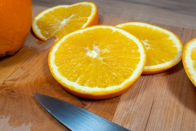 De nombreuses tranches d'orange se trouvent sur une planche de cuisine en bois. Agrumes frais.