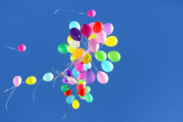 Photo de nombreux ballons multicolores volant dans le ciel bleu accessoires et décorations de vacances