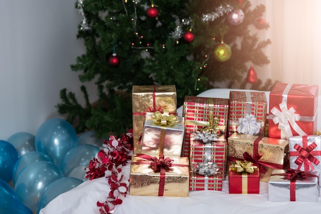 De nombreux cadeaux de Noël coffrets cadeaux sur une table avec arbre de Noël, vacances, cadeaux, nouvel an et concept de célébration