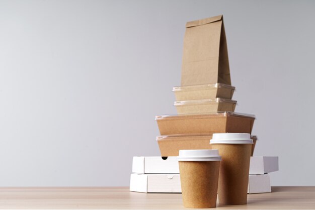 De nombreux contenants de nourriture à emporter, boîte à pizza, tasses à café et sacs en papier sur fond gris clair