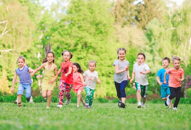 De nombreux enfants, garçons et filles courant dans le parc lors d&#39;une journée d&#39;été ensoleillée en tenue décontractée