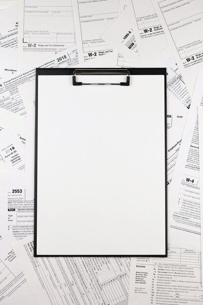 Photo de nombreux formulaires d'impôt en blanc et tablette se trouve sur la table des contribuables paperasse routine et le concept de la bureaucratie