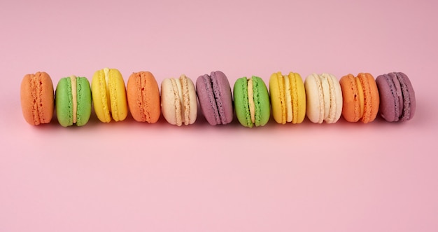 De nombreux gâteaux macarons ronds multicolores sur fond rose clair