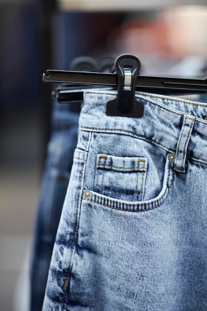 De nombreux jeans bleus sont suspendus à un rack dans le magasin de vêtements. Jeans ou pantalons en denim suspendus à un cintre.