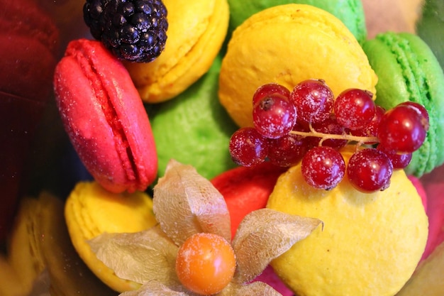 De nombreux macarons colorés avec de la crème sur la plaque blanche