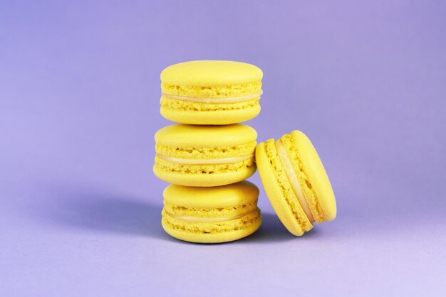 De nombreux macarons jaunes savoureux sur fond violet