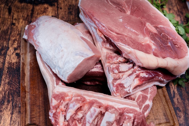 De nombreux morceaux de viande de porc fraîche sur une planche à découper en bois