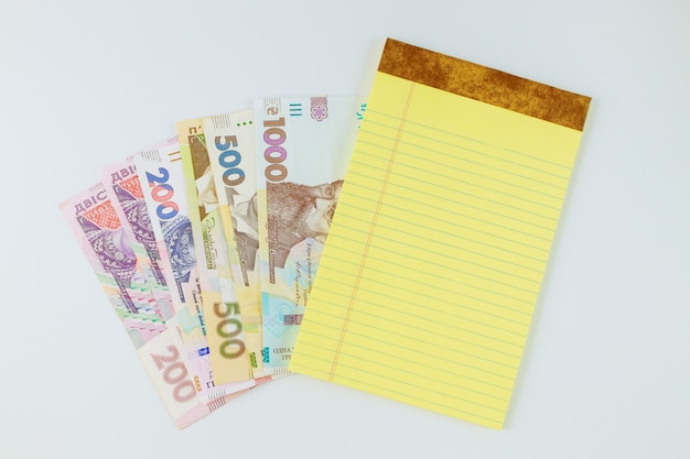 De nombreux nouveaux billets hryvnia ukrainienne dans le cahier jaune sur fond blanc