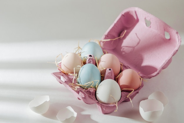 De nombreux œufs biologiques colorés dans une boîte à œufs avec des rayons de soleil. Compositions aux couleurs pastel.