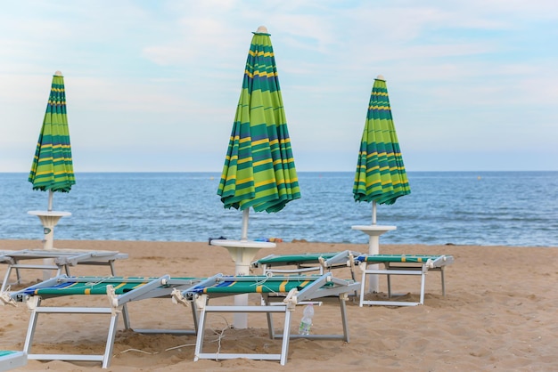 de nombreux parasols et chaises longues fermés sur une plage vide Concept de début ou de fin de saison