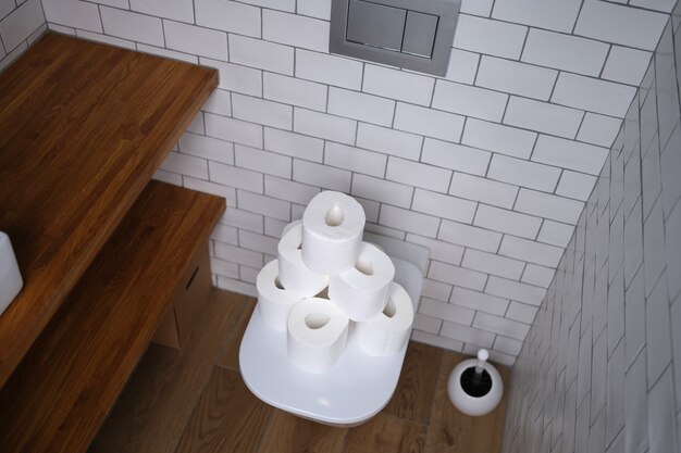 De nombreux rouleaux de papier blanc sont sur les toilettes dans les toilettes