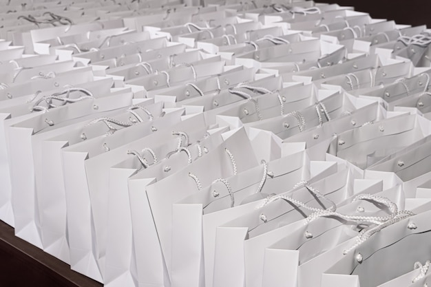 De nombreux sacs-cadeaux en carton blanc identiques sur fond sombre
