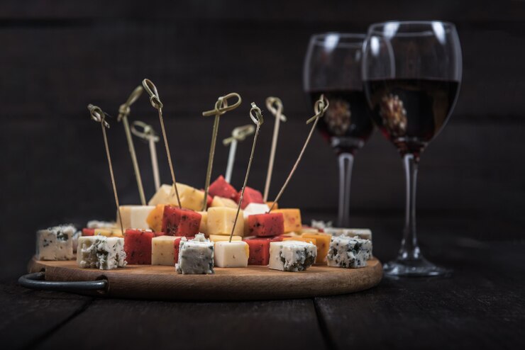 De nombreux types de fromages sur l'extrémité en bois d'un arbre avec du vin de roseau