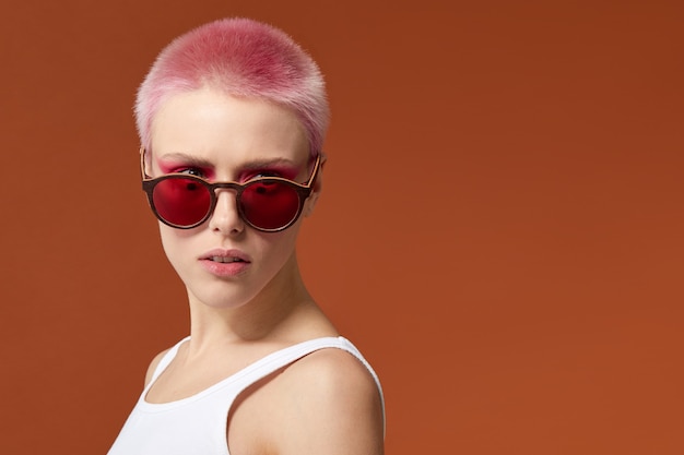 Non-conformiste jeune femme cheveux courts magenta rose avec des lunettes de soleil rouges