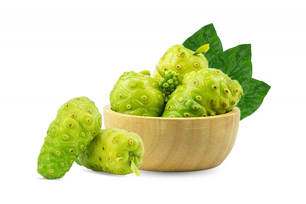 Noni ou Morinda Citrifolia et morceaux dans une tasse en bois, séparés sur fond blanc.