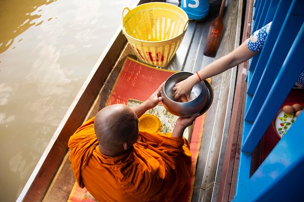 NONTHABURI THAÏLANDE 22 NOVEMBRE Thaïlandais priant mettre des offrandes de nourriture et de choses aux moines procession sur bateau dans la tradition de l'aumône à Wat Sai Yai le 22 novembre 2018 à Nonthaburi Thaïlande