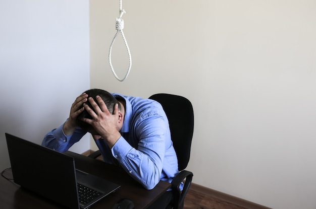 Noose est au-dessus de l'employé de bureau. Notion de suicide. Freelance en ligne pendant le temps de quarantaine. Travail à distance. Notion de chômage. Crise économique. Coronavirus. Stress au travail et dépression.