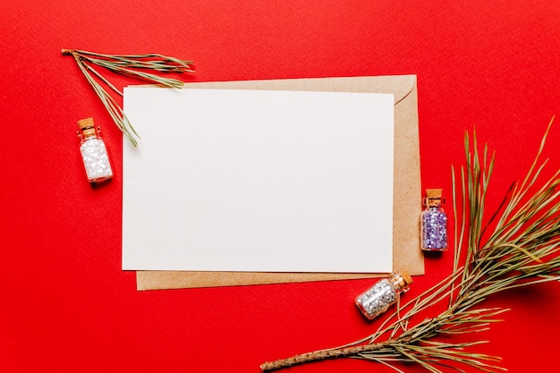 Note de Noël vierge avec branche de sapin et jouet d'épinette sur fond isolé rouge. Notion de nouvel an