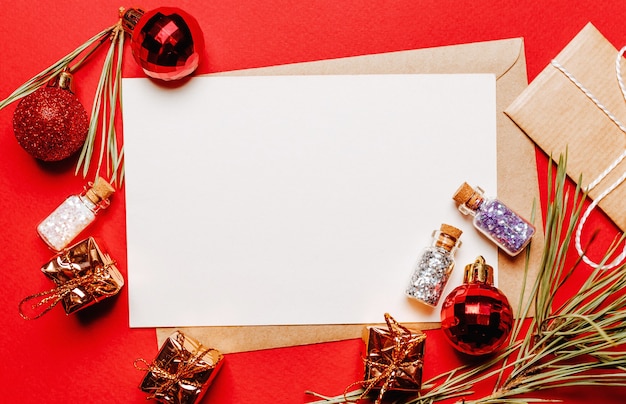 Photo note de noël vierge avec cadeau, branche de sapin et jouet sur rouge