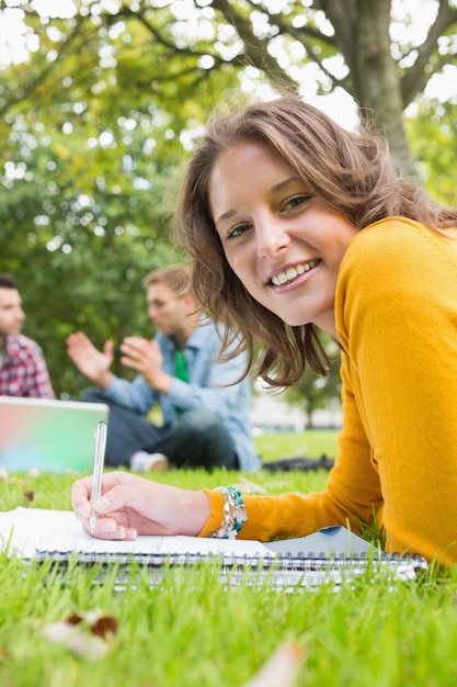 Notes d&#39;écriture féminine avec les étudiants utilisant un ordinateur portable dans le parc