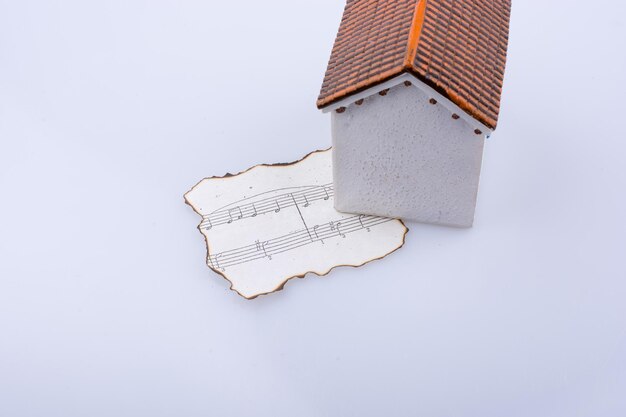 Notes de musique sur un papier brûlé sous une maison modèle