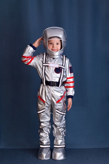 Notion d'astronaute. Portrait de petit garçon en costume de cosmonaute et casque sur fond bleu.