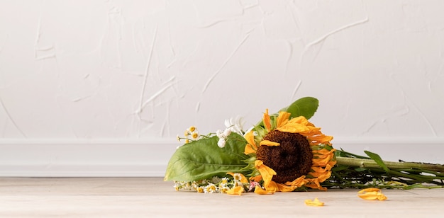 Notion d'automne. Un bouquet de fleurs fanées et un tournesol au sol. Bannière