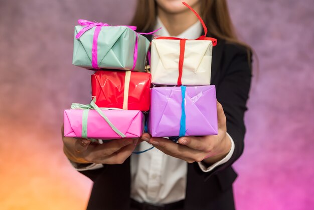 Notion de cadeaux de Noël. Belle femme tenant des boîtes à cadeaux colorées