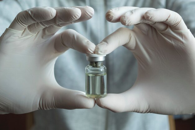 Photo notion de coronavirus, covid-19. un homme en gants blancs médicaux tient une bouteille de vaccin.