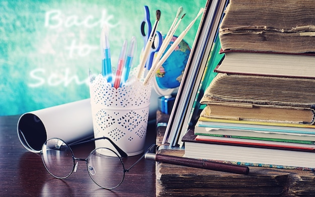 Notion d'éducation. Une pile de manuels et un livre sur le bureau avec des lunettes et un ordinateur. Pomme de petit-déjeuner scolaire et devoirs.
