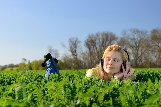 Notion de musique. Jeune femme avec des écouteurs écoutant de la musique sur le pré