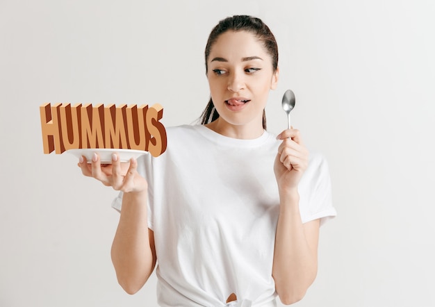 Notion de nourriture. Modèle tenant une assiette avec des lettres de houmous