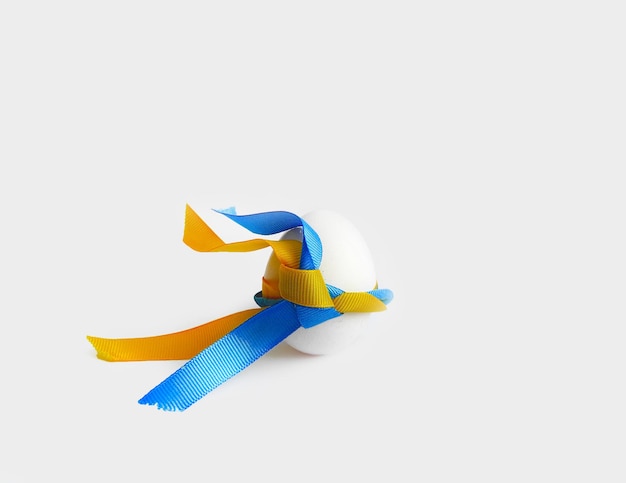 Notion de Pâques. L'œuf blanc est en gros plan avec des rubans jaune-bleu. Symbolisme ukrainien, drapeau de l'Ukraine