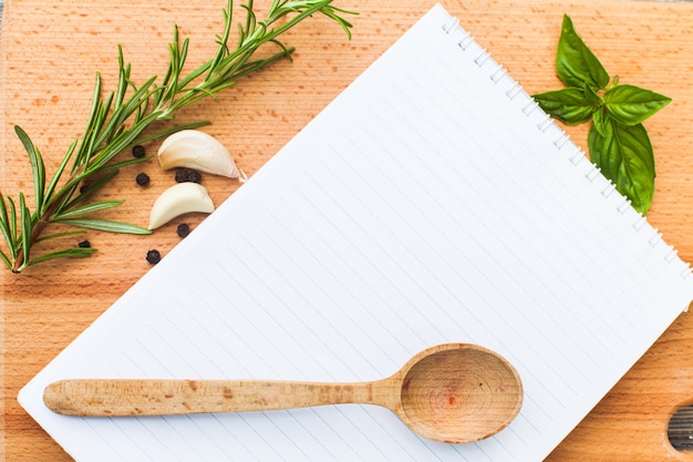 Notion de recette. Feuille de papier vierge sur une planche de bois avec des épices