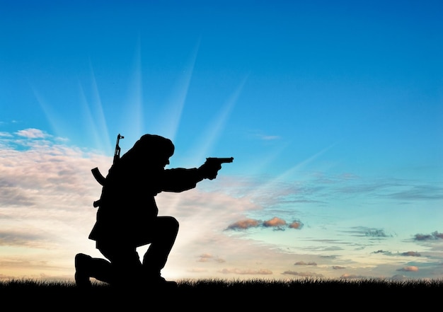 Notion de terrorisme. Silhouette d'un terroriste avec un fusil sur fond de coucher de soleil