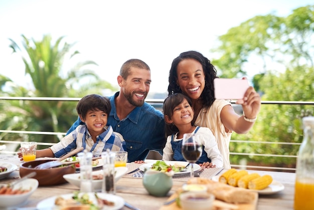 Notre belle petite famille est parfaite Photo d'une belle jeune famille prenant des photos avec un téléphone portable tout en savourant un repas ensemble à l'extérieur