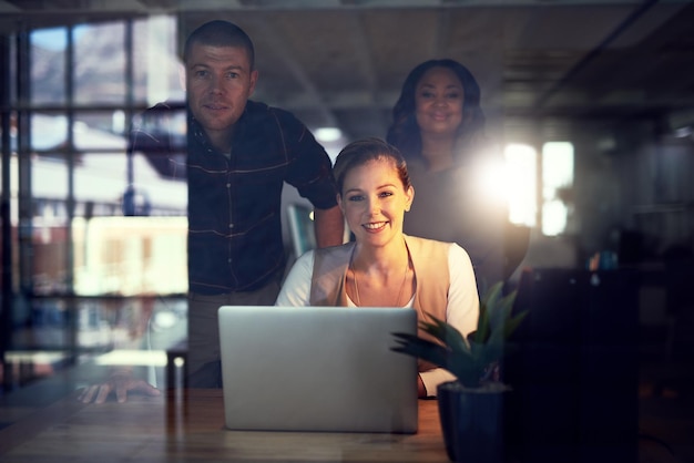 Notre équipe de grands penseurs Portrait d'un groupe de collègues de travail travaillant ensemble sur un ordinateur portable et échangeant des idées au bureau tout en regardant la caméra