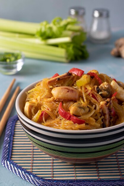 Photo noudles de riz funchoza avec des fruits de mer pasta cellophane moules calmar et poulpe repas asiatique sain collation dans un bol sur un fond bleu clair format vertical