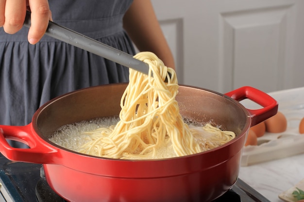 Nouilles asiatiques bouillies à la main de femme asiatique (Mie Telur ou bakmi), processus de cuisson dans la cuisine