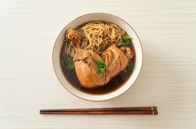 Nouilles au poulet braisé dans un bol de soupe brune - style de cuisine asiatique