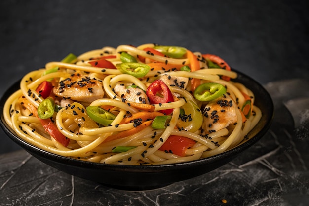 Nouilles au poulet et légumes ou Chow Mein dans un bol noir sur fond sombre Espace de copie gratuit Mise au point sélective