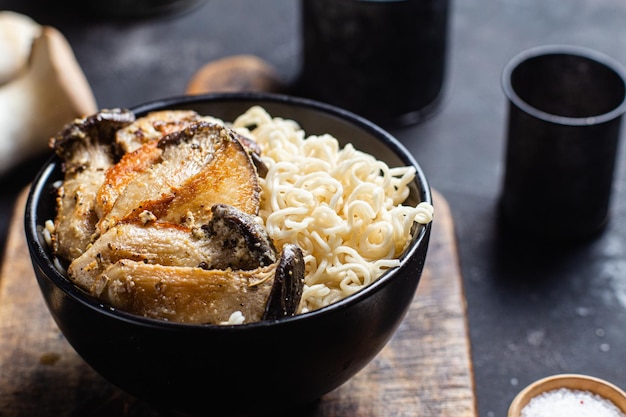 Nouilles aux champignons eringi dans une assiette noire