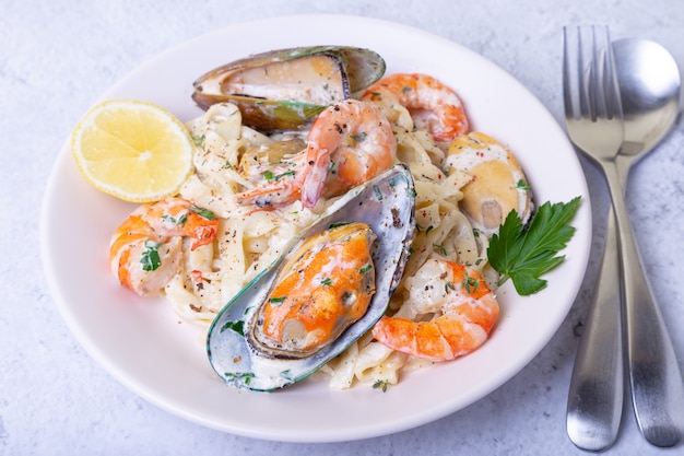 Nouilles aux fruits de mer. Pâtes maison aux crevettes et moules dans une sauce crémeuse. Plat italien traditionnel. Fermer.