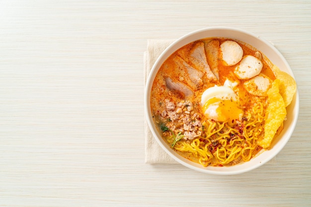 Nouilles aux œufs avec porc et boulettes de viande dans une soupe épicée