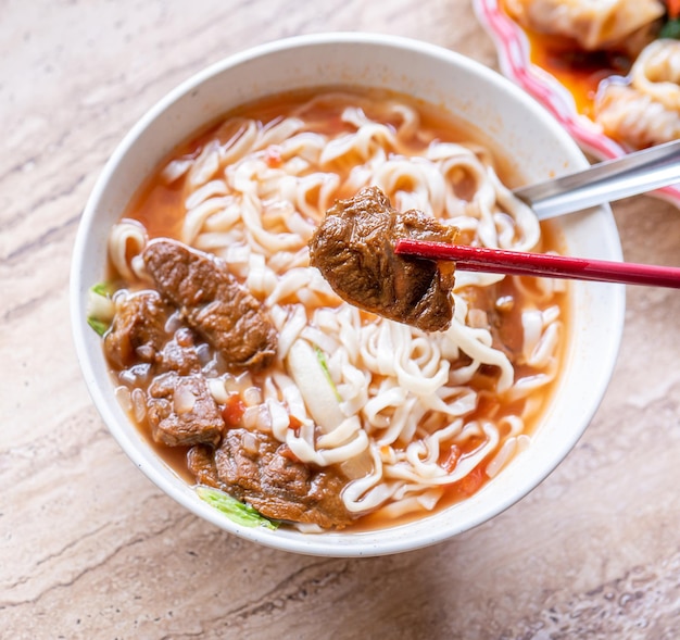 Nouilles de boeuf Taïwan ramen repas avec bouillon de sauce tomate dans un bol sur une table en bois clair célèbre cuisine de style chinois gros plan vue de dessus espace de copie