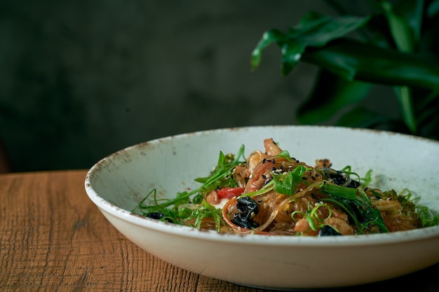 Nouilles cellophane aux crevettes et légumes, champignons shiitake dans une assiette blanche. Wok de nouilles de riz