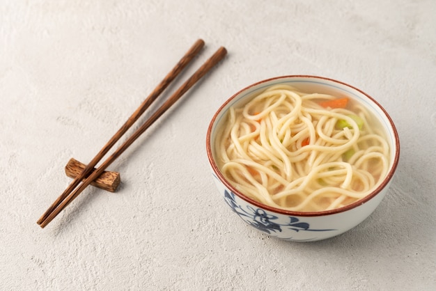 Photo nouilles chinoises ou udon aux légumes et baguettes