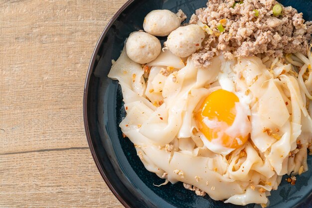 nouilles épicées séchées avec du porc haché, des boulettes de viande et des œufs - style cuisine asiatique