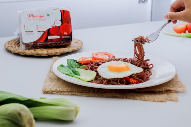 Nouilles frites servies avec des œufs au plat et des légumes sur une assiette