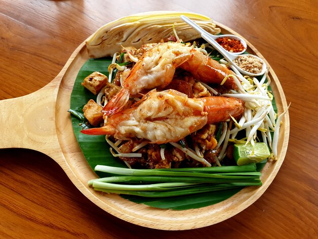 Nouilles frites à la thaïlandaise avec crevettes de rivière sur une plaque en bois